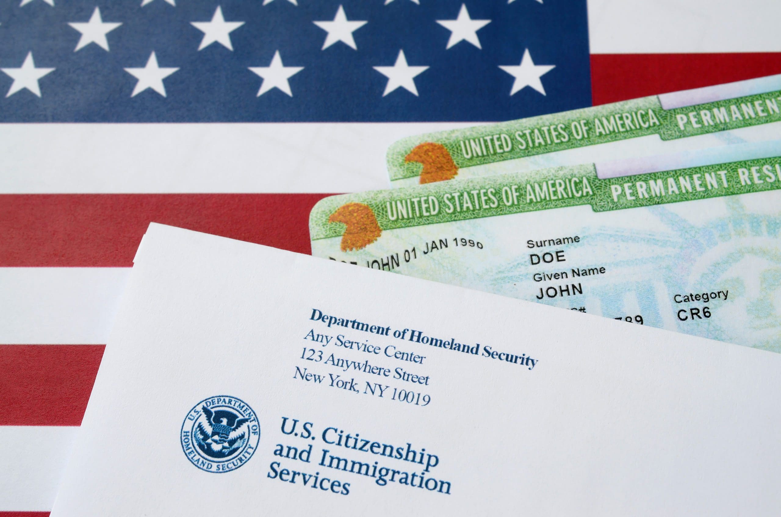 https://onlinevisas.com/wp-content/uploads/2022/09/United-States-Permanent-resident-green-cards-from-dv-lottery-lies-on-United-States-flag-with-envelope-from-Department-of-Homeland-Security-scaled.jpeg